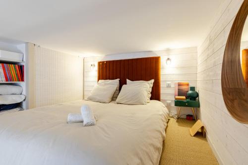 - une chambre avec un grand lit blanc et une tête de lit en bois dans l'établissement Surfing-House Biarritz, à Biarritz
