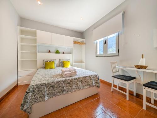 a bedroom with a bed with yellow pillows and a desk at Casas das Hortas, Studio Vista Jardim e Serra in Seixal
