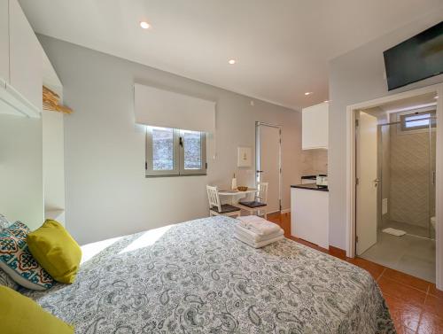 a bedroom with a large bed and a kitchen at Casas das Hortas, Studio Vista Jardim e Serra in Seixal
