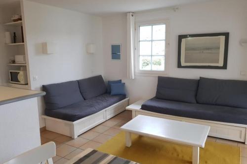 un salon avec des canapés bleus et une table dans l'établissement Apartment T3 - area with pool and activities, à Urrugne