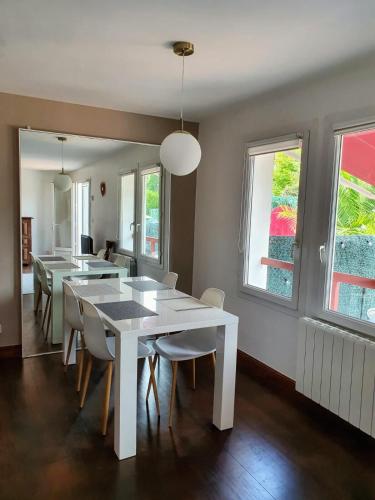 une salle à manger avec une table et des chaises blanches dans l'établissement Duplex with terrace between beach and bay - Hendaye, à Hendaye