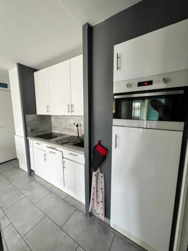 une cuisine avec des armoires blanches et un réfrigérateur blanc dans l'établissement Superbe T2 face mer piscine, à Six-Fours-les-Plages