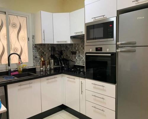a kitchen with white cabinets and a stainless steel refrigerator at well-equipped apartment in Marrakech