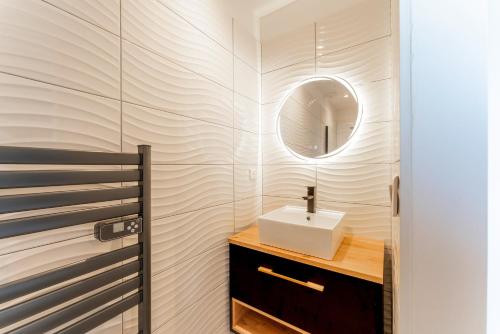 un bagno con lavandino e specchio di Appartement avec Jacuzzi Sauna a Saint-Géniès-de-Malgoirès