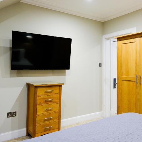 a bedroom with a flat screen tv on a wall at Glen Mhor Hotel at Uile-bheist 'Brewstillery' in Inverness