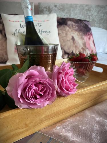 a bottle of wine and pink roses on a tray at Abingdon House in Torquay
