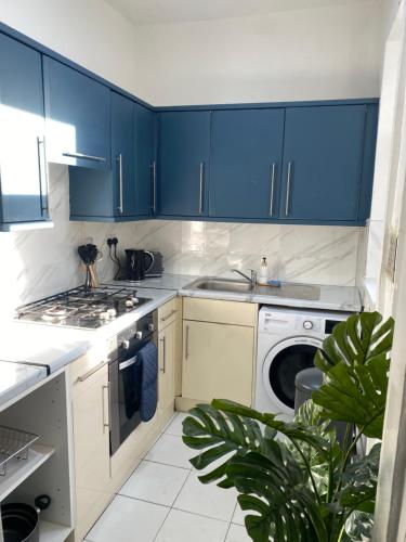 eine Küche mit blauen Schränken und einer Waschmaschine in der Unterkunft Modern Townhouse-Free Parking-Games Room-Fast W-iFi in Manchester