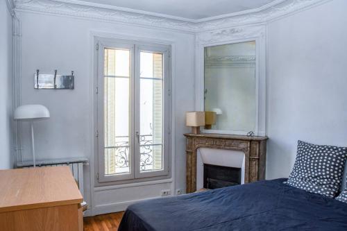 une chambre blanche avec un lit et une cheminée dans l'établissement Oberkampf, à Paris