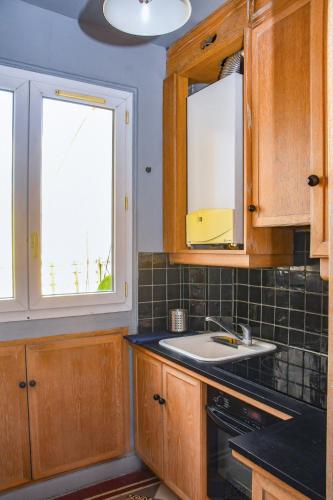 - une cuisine avec des placards en bois, un évier et 2 fenêtres dans l'établissement Oberkampf, à Paris