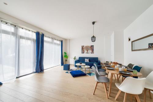 un salon avec un canapé bleu, des tables et des chaises dans l'établissement Stylish 3 bdr & Garden Oasis on the Edge of Paris, à Saint-Mandé