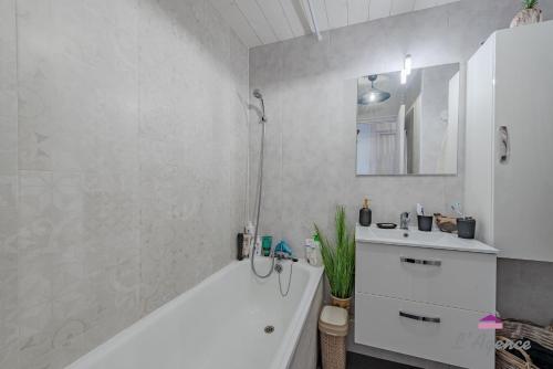 a white bathroom with a tub and a sink at Le Nid Cosy accès direct sur la mer in Le Barcarès