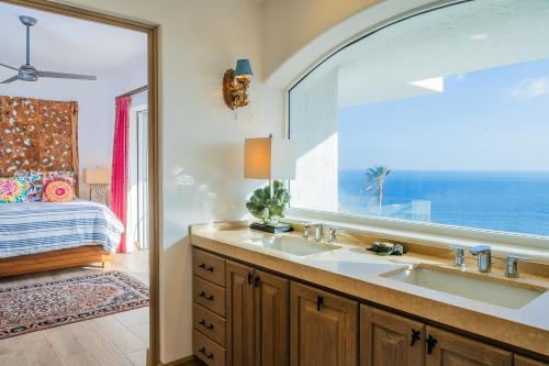 a bathroom with a sink and a window and a bed at Villa Esencia Del Mar in Cabo San Lucas