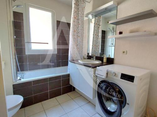 une salle de bain avec une machine à laver et un lavabo dans l'établissement T3 renove dans residence avec piscine et garage Capacite max 6 personnes, à Sète