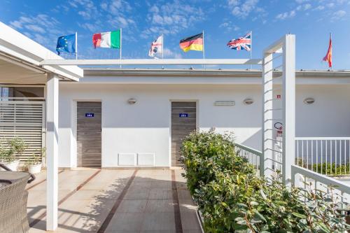 a white building with flags on top of it at Hotel Belvir in Villasimius