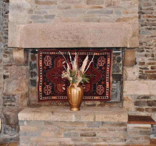 a vase with flowers in it sitting on a brick wall at Country House La Feronnière in Le Mesnil-Amand