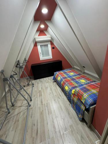 a attic bedroom with a bed and a red wall at La casina di Ginevra in Marina di Massa