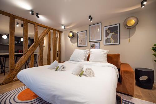 Cette chambre comprend un grand lit blanc et des poutres apparentes. dans l'établissement CIA - Home on Grands Boulevards, à Paris