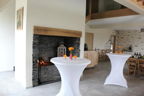 2 mesas blancas en una habitación con chimenea en Cafcauter en Sint-Pieters-Kapelle