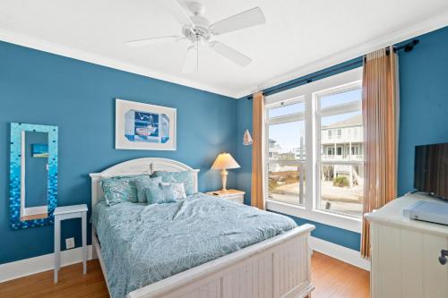 a blue bedroom with a bed and a window at Experience luxury at On The Rocks, spacious 4 bedroom retreat with private pool! in Ocean Isle Beach