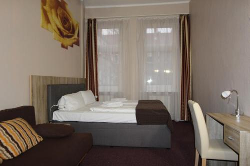 a bedroom with a bed and a couch and a window at City Hotel Gotland in Berlin