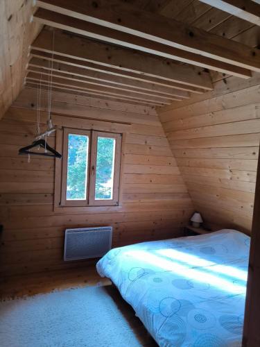 Ce lit se trouve dans une chambre en bois dotée d'une fenêtre. dans l'établissement Merveilleux chalet à la montagne, à La Colmiane