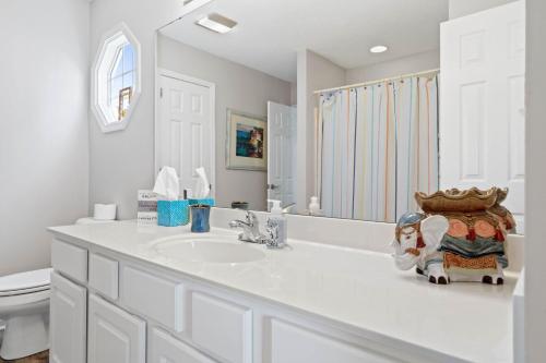 a white bathroom with a sink and a toilet at 4 BD 3 BA Cottage on Ocean Isle Beach with Water View & Community Pool! in Ocean Isle Beach