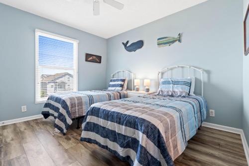 two beds in a bedroom with blue walls at 4 BD 3 BA Cottage on Ocean Isle Beach with Water View & Community Pool! in Ocean Isle Beach