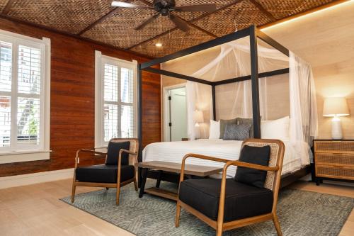 1 dormitorio con 1 cama con dosel y 2 sillas en The Key West Hotel, en Key West