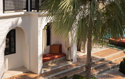 a palm tree next to a porch with a bench at Villa Maroc Resort in Pran Buri