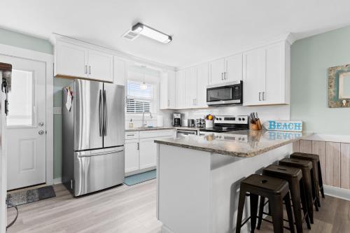 a kitchen with white cabinets and a stainless steel refrigerator at Remodeled Beach Happy 4 Bedroom 2 Bathroom for 9 Guests! in Ocean Isle Beach