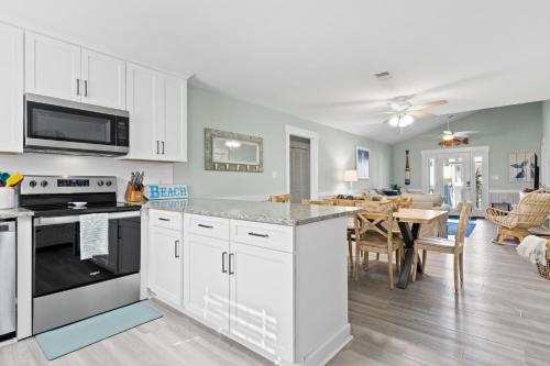 a kitchen with white cabinets and a dining room at Remodeled Beach Happy 4 Bedroom 2 Bathroom for 9 Guests! in Ocean Isle Beach