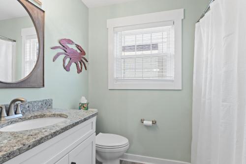 a bathroom with a sink and a toilet and a window at Remodeled Beach Happy 4 Bedroom 2 Bathroom for 9 Guests! in Ocean Isle Beach
