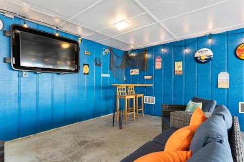 a blue room with a couch and a tv on a wall at Remodeled Beach Happy 4 Bedroom 2 Bathroom for 9 Guests! in Ocean Isle Beach