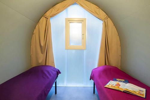 Cette chambre comprend deux lits et une porte avec fenêtre. dans l'établissement Camping 2 étoiles - Piscine - ccab0if, à Saint-Sozy