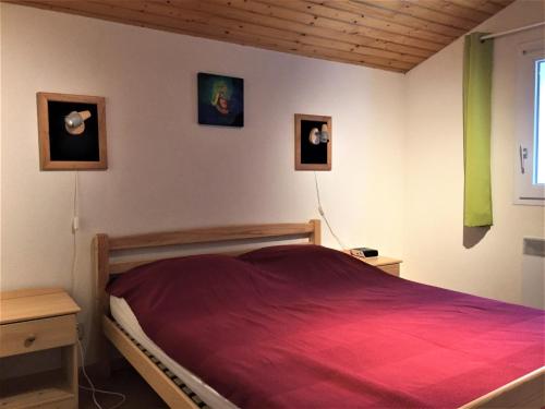 - une chambre avec un lit rouge et deux photos sur le mur dans l'établissement Detente et confort proche de la mer, à Saint-Trojan-les-Bains