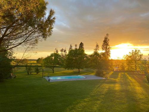 une piscine dans un champ avec un coucher de soleil en arrière-plan dans l'établissement Domaine de Treuillaud climatisé piscine privée, à Villers-les-Ormes