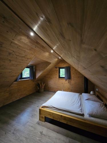 a large bed in a room with a wooden ceiling at Apardo Chaty Březka - Trojka in Březka