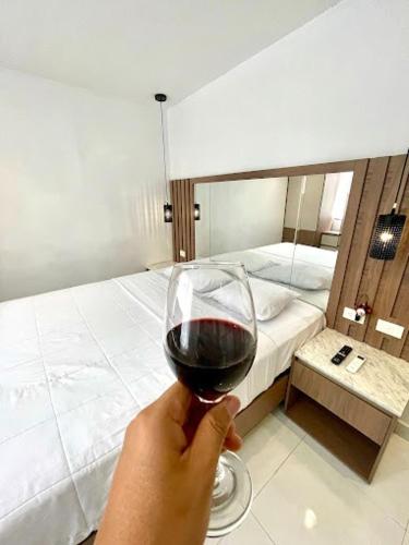 a person holding a glass of wine in front of a bed at Novapark Kennedy Hotel in Guayaquil