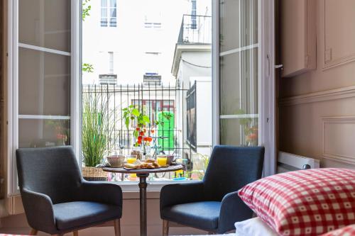 une chambre avec deux chaises, une table et une fenêtre dans l'établissement Artisan Lofts courtyard Opéra, à Paris