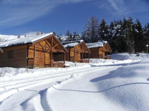 a row of wooden cabins in the snow at Chalet Les Balcons du Grand Puy in Seyne