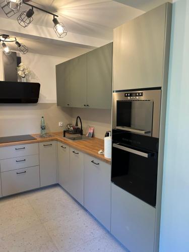 a kitchen with white cabinets and black appliances at Domek Marzenie in Radawa