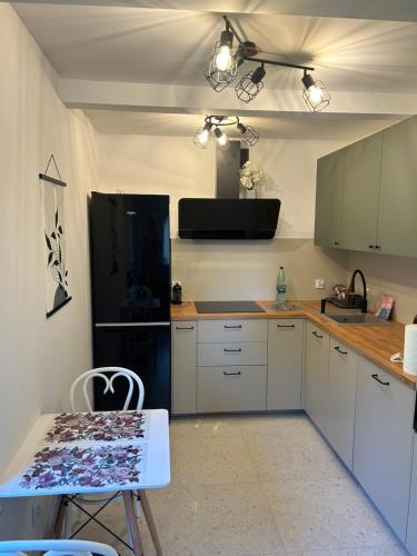 a kitchen with white cabinets and a black refrigerator at Domek Marzenie in Radawa