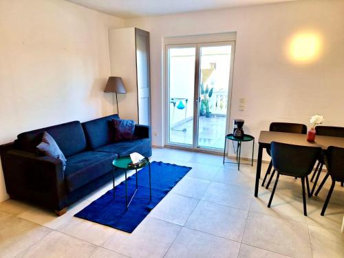 a living room with a blue couch and a table at Apartments C'EST LA SEA - Whirlpool-Suite oder Dachterrassen-Suite in Neusiedl am See