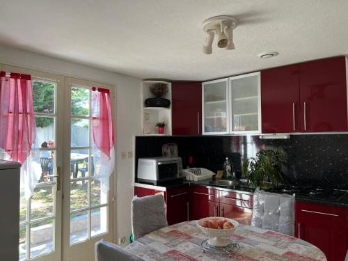 - une cuisine avec des placards rouges et une table avec un bol dans l'établissement Charmante maison avec jardin intime, à Grand-Village-Plage
