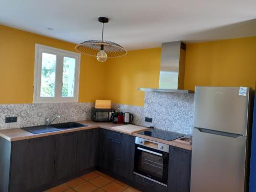 - une cuisine avec des murs jaunes et un réfrigérateur blanc dans l'établissement Maison avec terrasse à Vert Bois, à Dolus-d'Oléron
