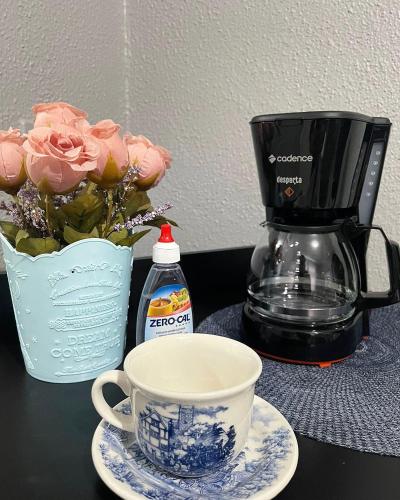 a cup of coffee and a vase of pink roses at Apartamento completo com garagem!Casa Taíba! in Fortaleza
