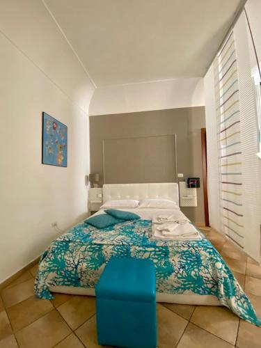 a bedroom with a large bed and a blue stool at Casa Calles in Siracusa