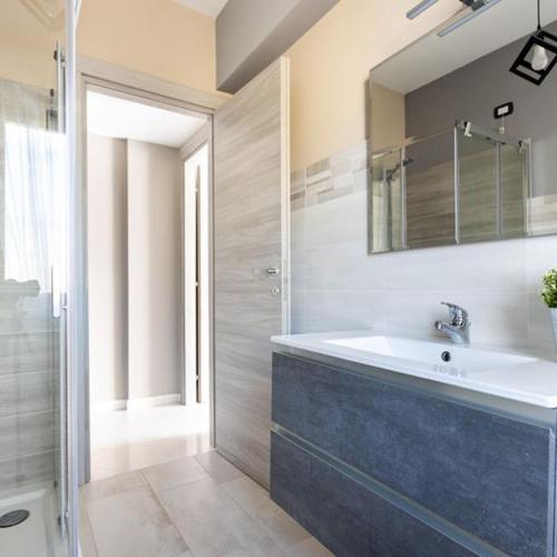 a bathroom with a sink and a mirror and a shower at Casa Libeccio in Quartu SantʼElena