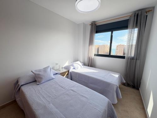 two beds in a room with a window at ACV- Terrazas II-2ª linea planta 9 este in El Borseral