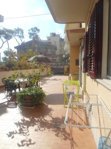 a patio with tables and chairs and an umbrella at Appartamenti turistici di Gabriele 20 mt dal mare in Pineto